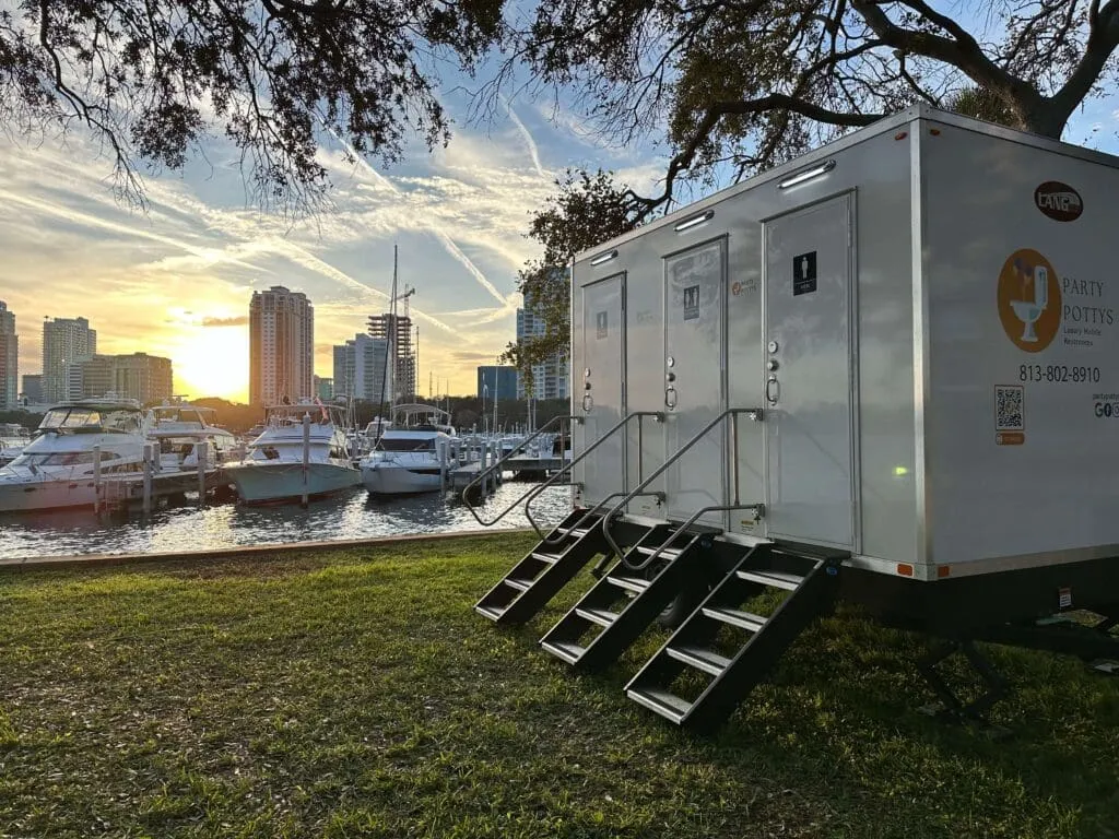 Party Pottys luxury restroom trailer parked on the grass at a St. Petersburg marina at sunset